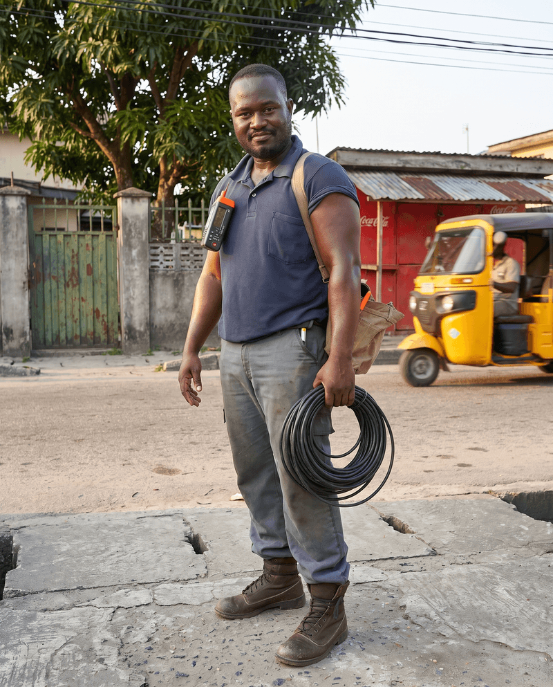 An electrician on a Port Harcourt street with a tool bag and a coil of cable